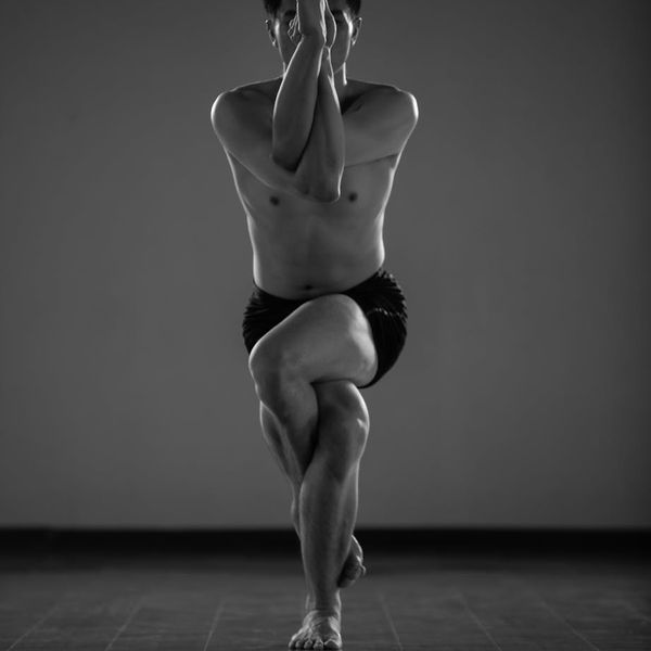Person in a focused warrior yoga pose in a minimalist studio.